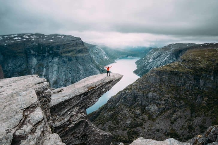 Man travelling sitting on high rock overlooking landscape