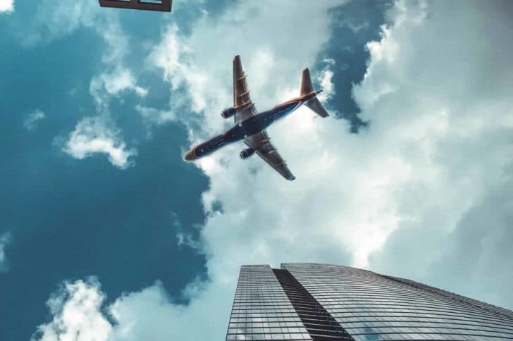 A plane flying through the sky in between two sky scraper buildings.