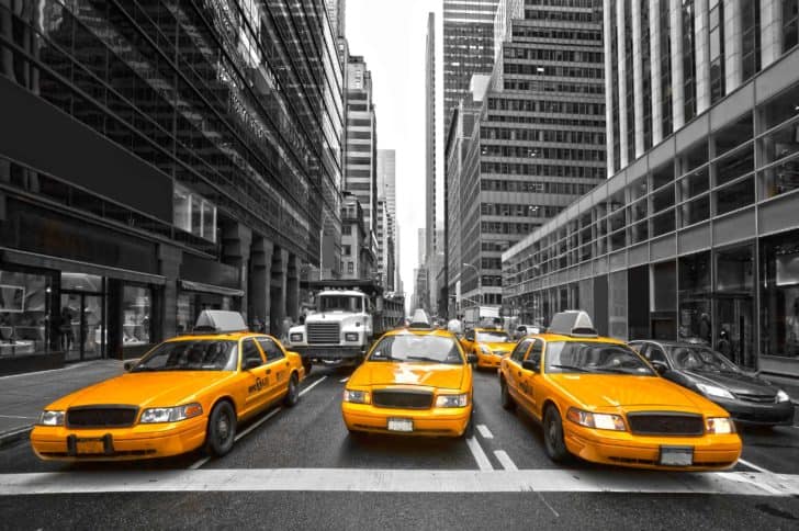 Three yellow taxis travelling through New York