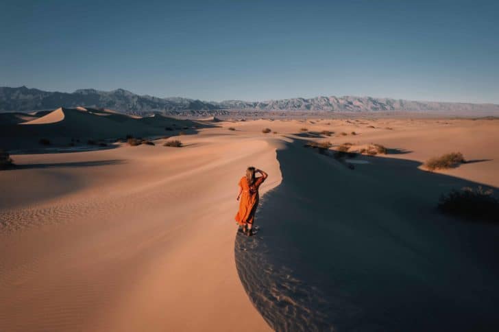 Woman in orange dress walking through desert